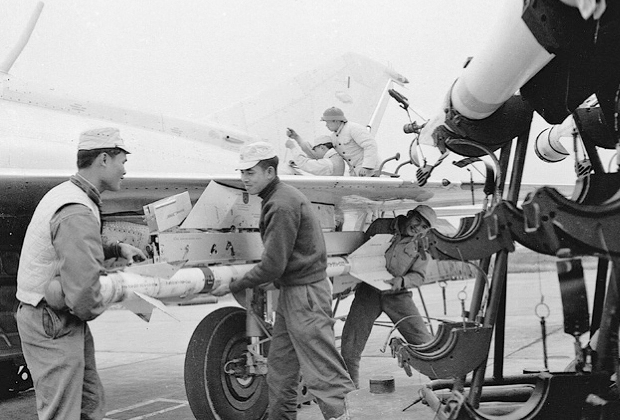 VPAF technicians load an R-3S "Atoll" air-to-air missile aboard a wing pylon of a MiG-21.